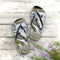 Flip-flops with a waterfall scene on a wooden deck with small plants.