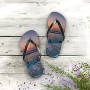Flip-flops with a sunset ocean wave design on a wooden surface.