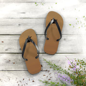 Brown flip-flops on a weathered wooden deck with scattered flower petals.