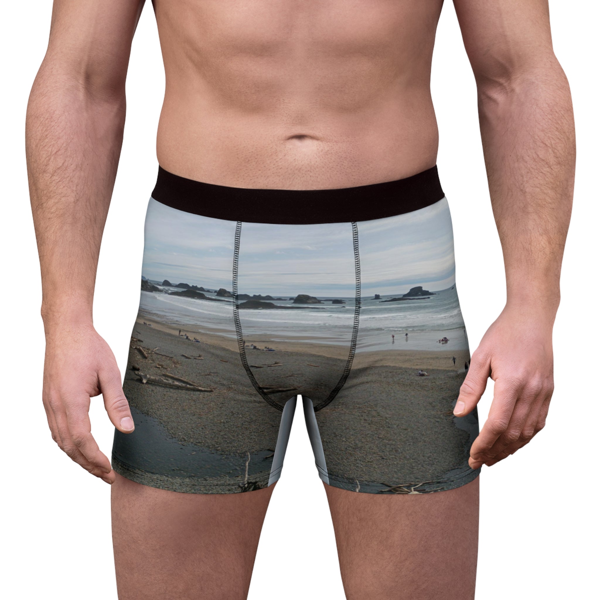 Man wearing grey patterned boxer briefs on a beach.