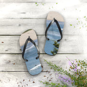 Flip-flops with a surfing wave graphic on a weathered wooden surface.