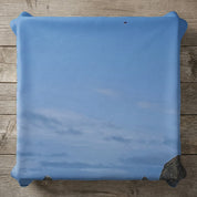 Blue sky with clouds and rocky outcropping above a wooden surface.