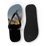 Black flip-flops with a sunset landscape print on the soles.