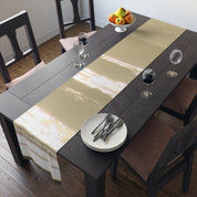 Dark wooden table set for dinner with gold runner, plates, and wine glasses.