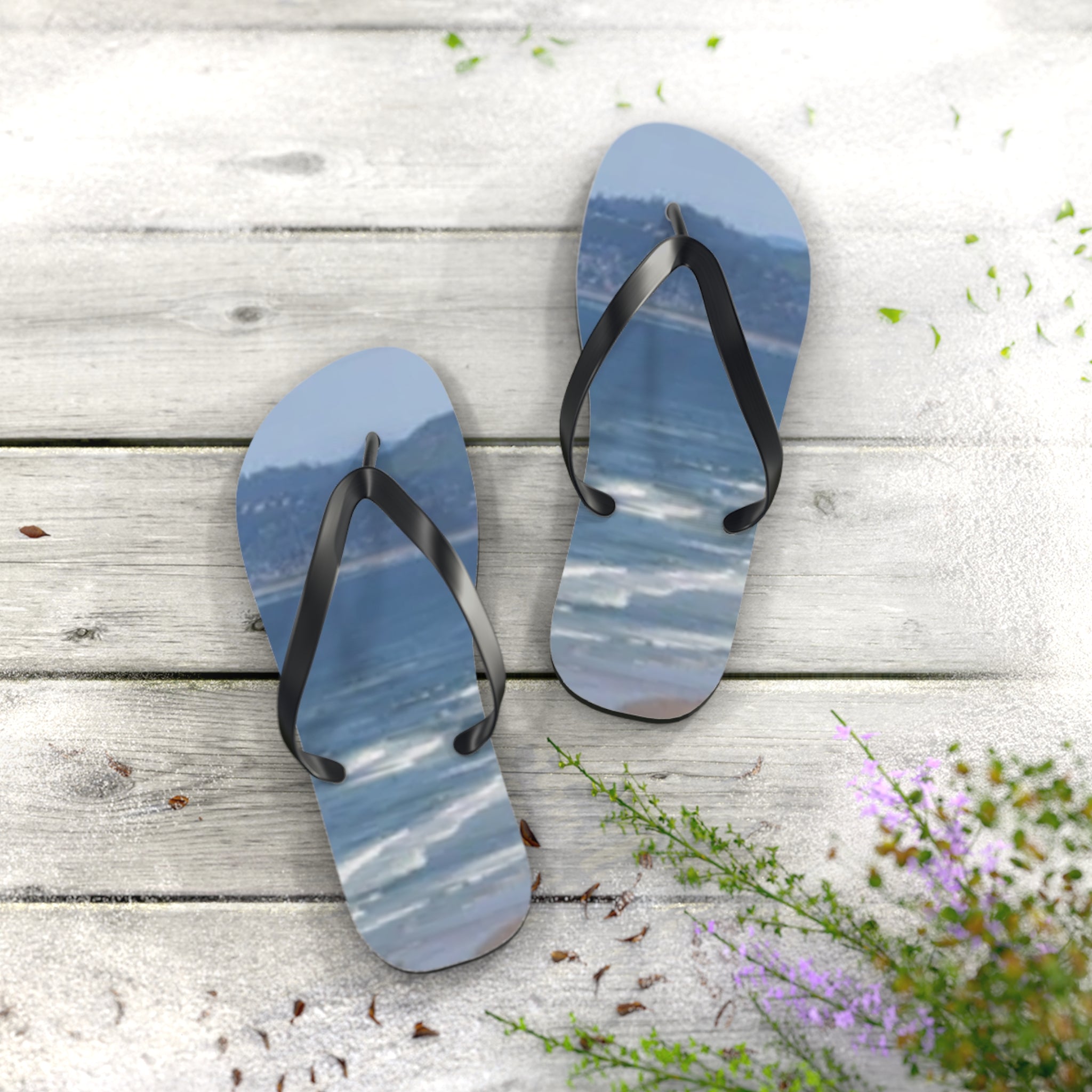 Flip-flops with a beach scene printed on the insoles lie on a weathered wooden surface.