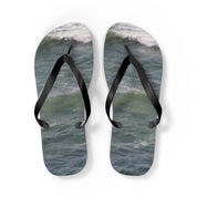 Pair of black flip-flops with ocean waves printed on the soles.