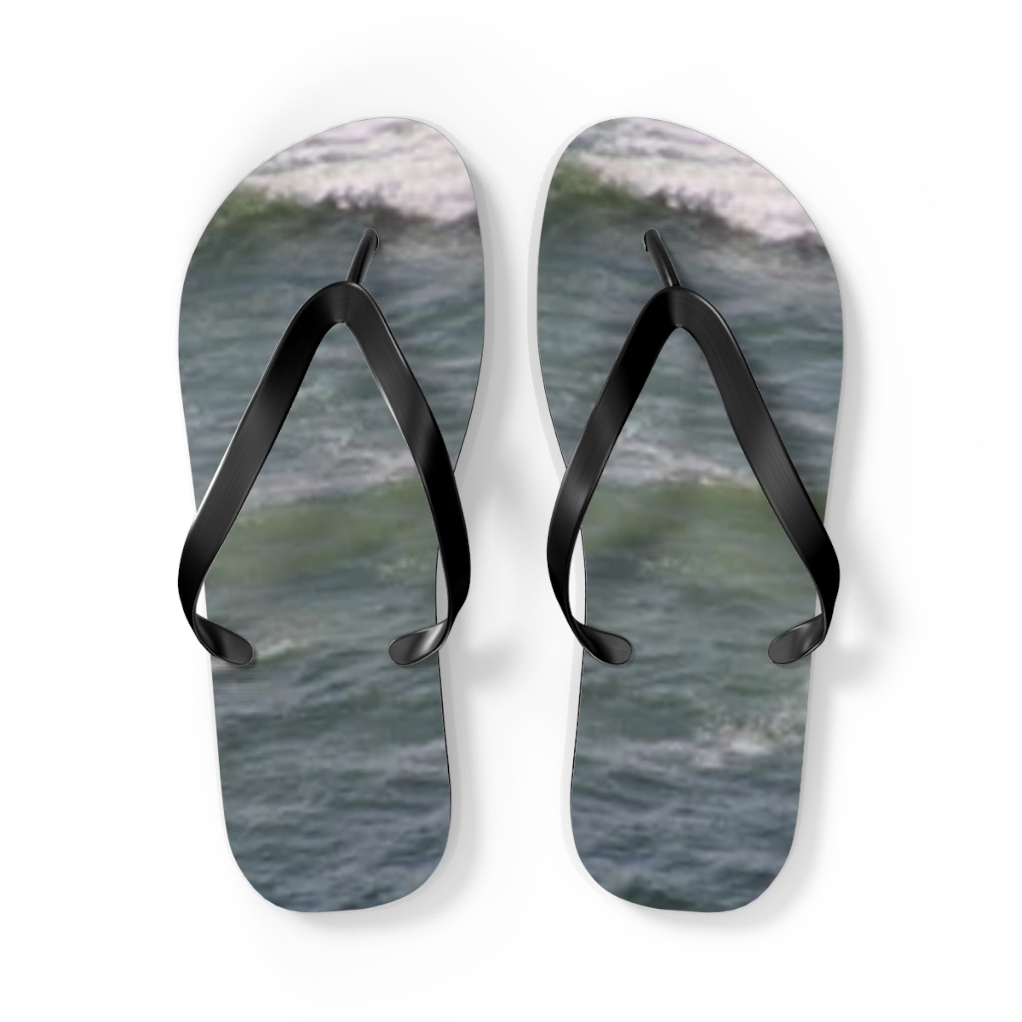 Pair of black flip-flops with ocean waves printed on the soles.