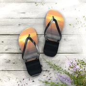 Flip-flops with a sunset ocean reflection on a wooden deck.