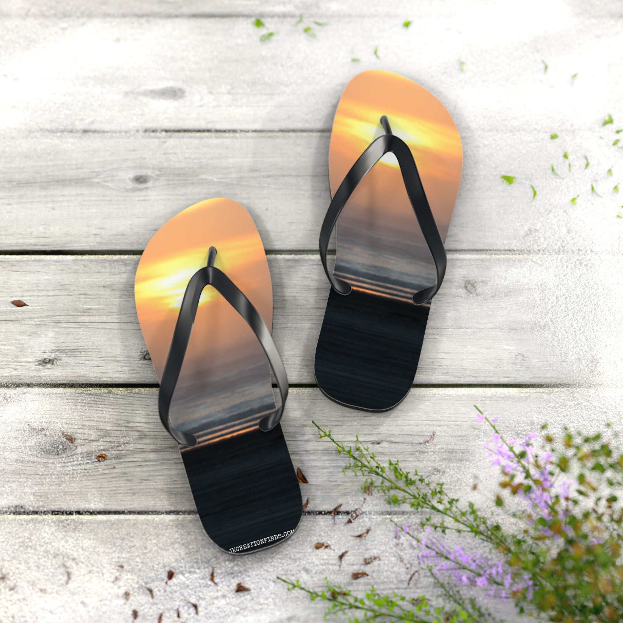 Flip-flops with a sunset ocean reflection on a wooden deck.