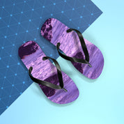 Purple ocean wave flip-flops with black straps on a blue background.