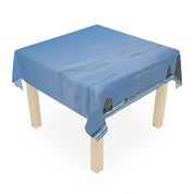 Tablecloth draped over a wooden table featuring a coastal seascape with rock formations.