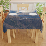 Blue tablecloth with a mountain landscape pattern on a wooden table.