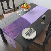 Table runner with purple and pink abstract landscape pattern on a dark wood table.