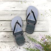 Light blue flip-flops with ocean scene imprinted on soles on wooden deck.