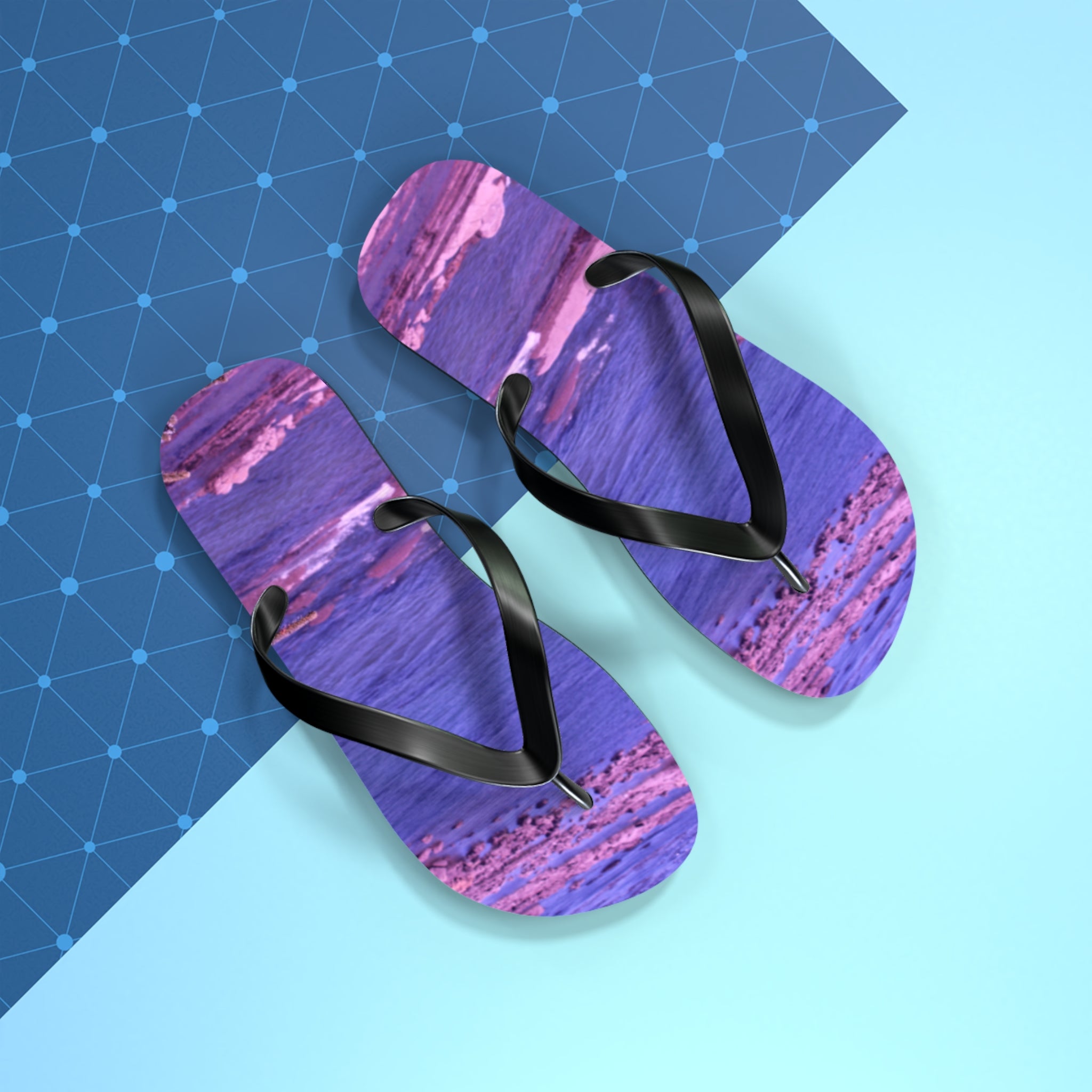 Purple and pink abstract pattern flip-flops with black straps on blue background.