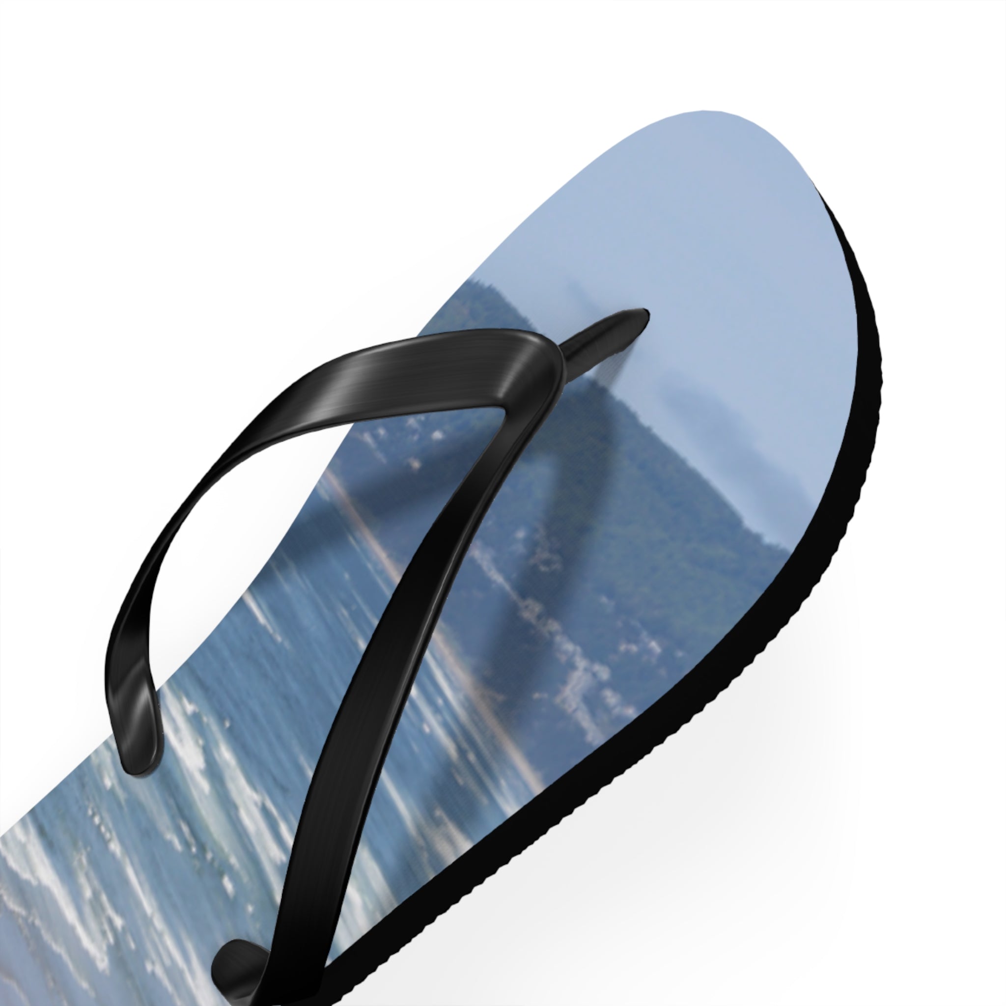 Black flip-flop with ocean wave and beach scenery on sole.
