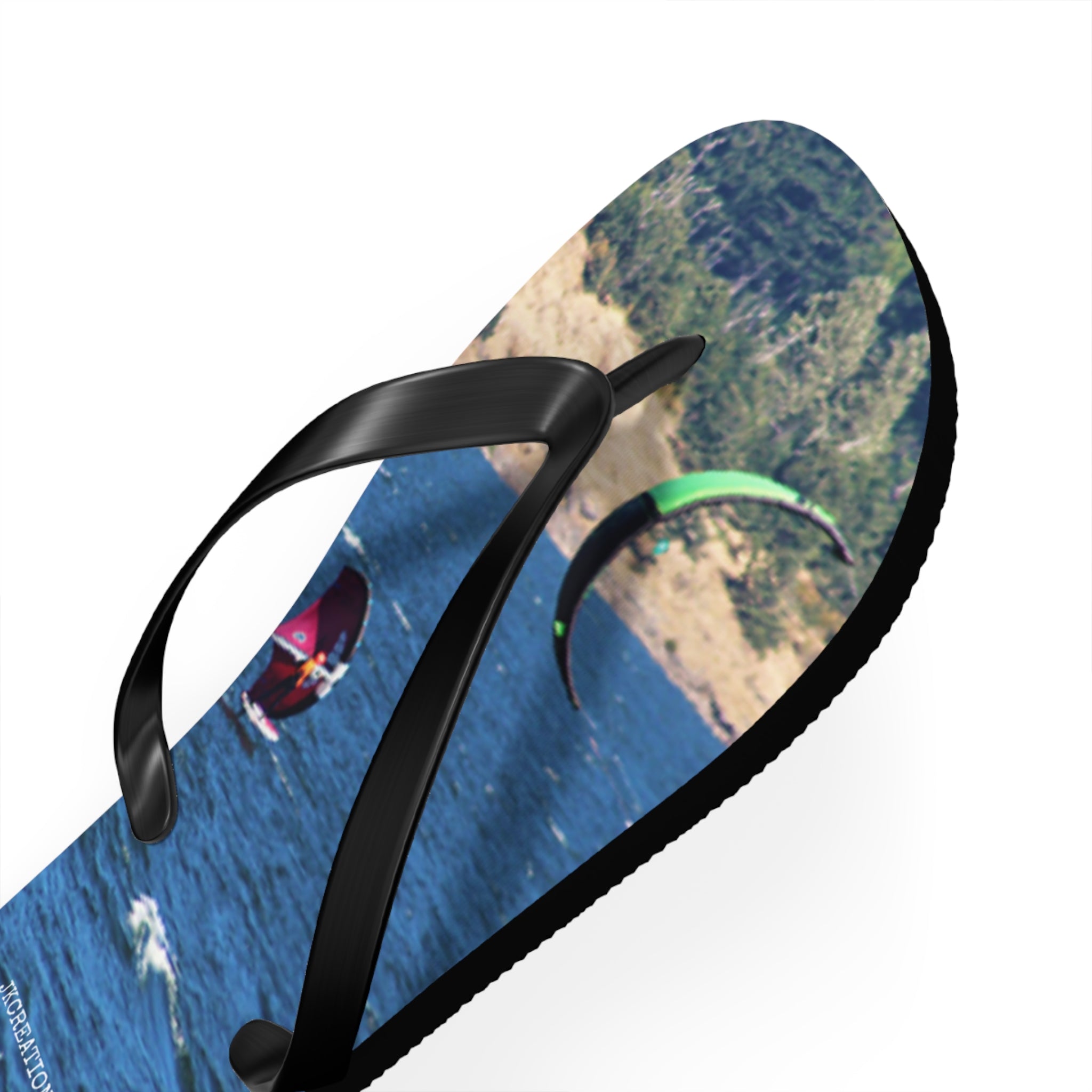 Flip-flops with kitesurfers on water and coastal landscape.