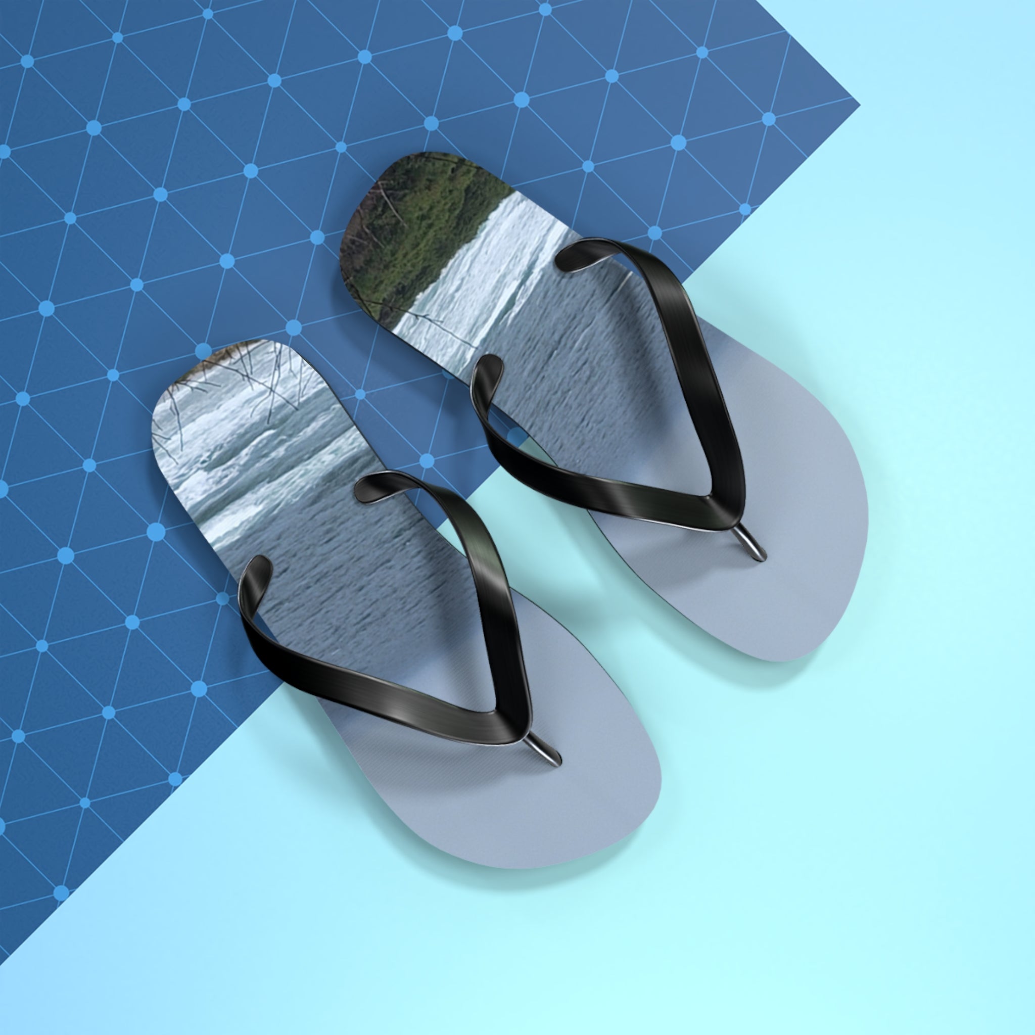 Flip-flops with a waterfall scene on the soles, on a blue grid background.