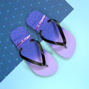 Purple flip-flops with a sunset beach scene on a blue geometric background.