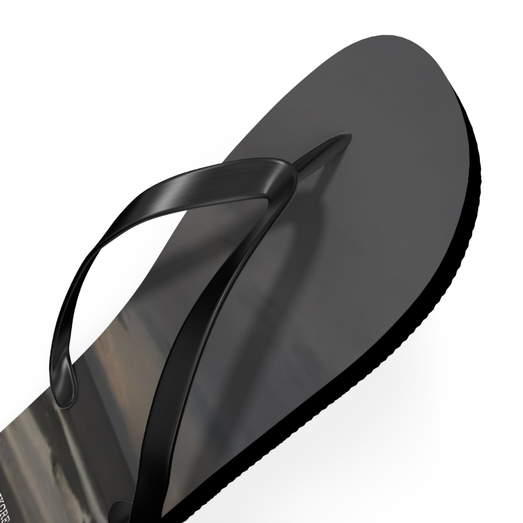 Black flip-flop with a reflective surface displaying a landscape.