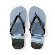 Flip-flops with ocean waves and coastal foliage printed on soles.