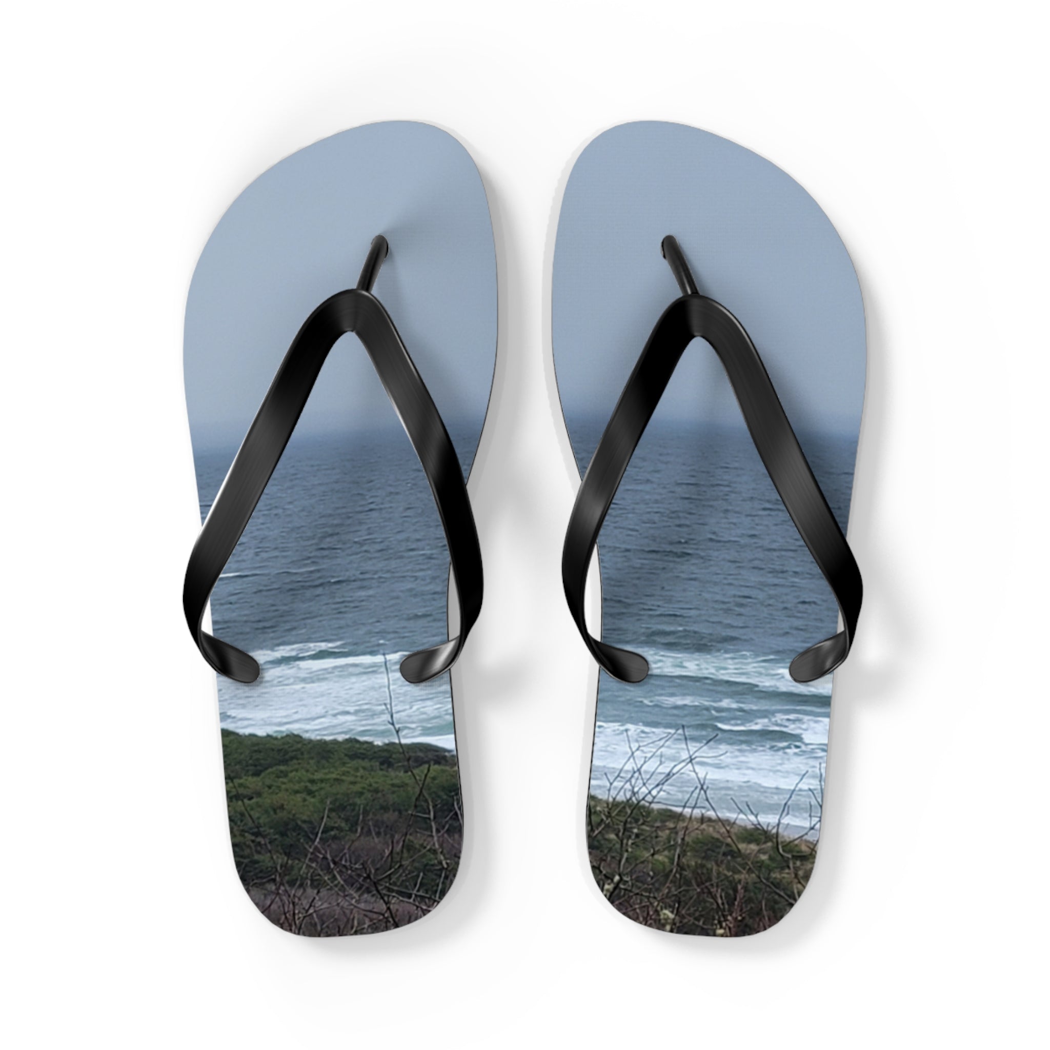 Flip-flops with ocean waves and coastal foliage printed on soles.