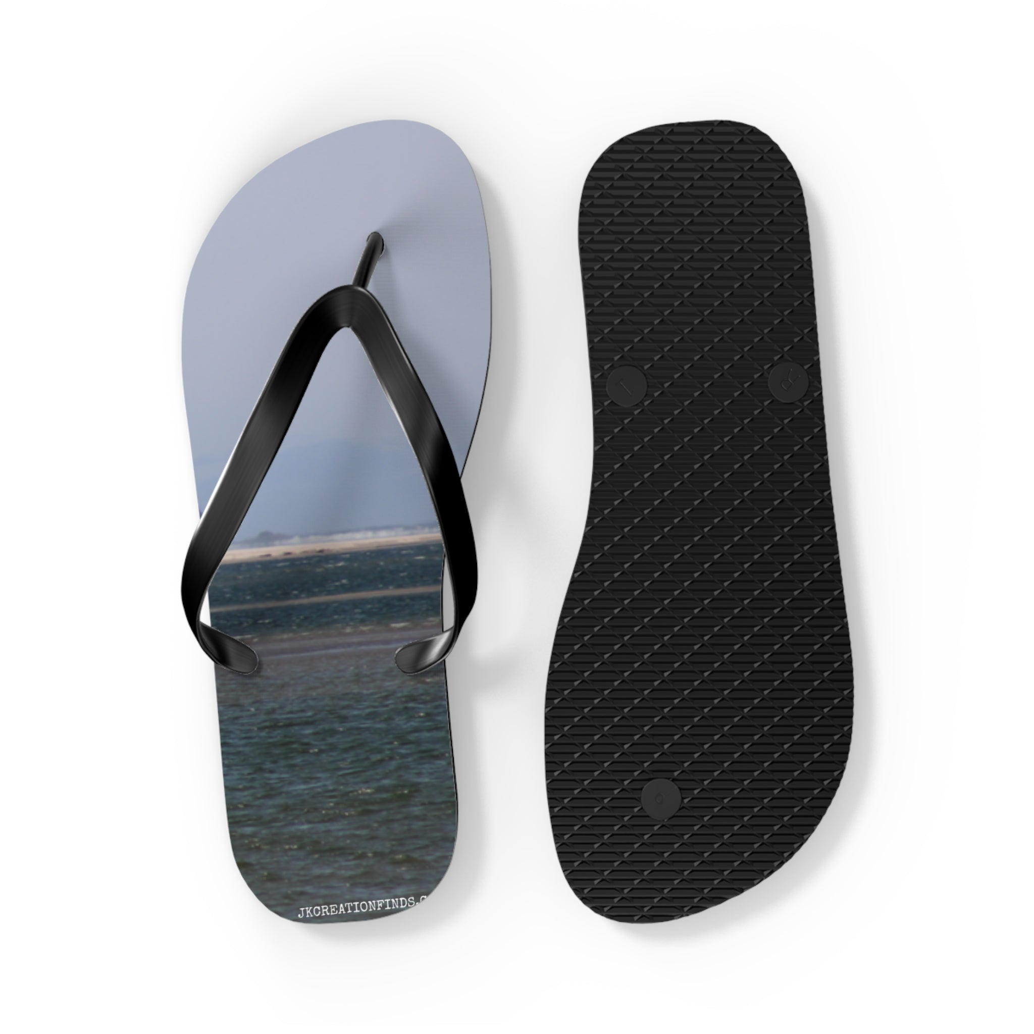 Flip-flops with a beach landscape design, one shown open and the other sole up.