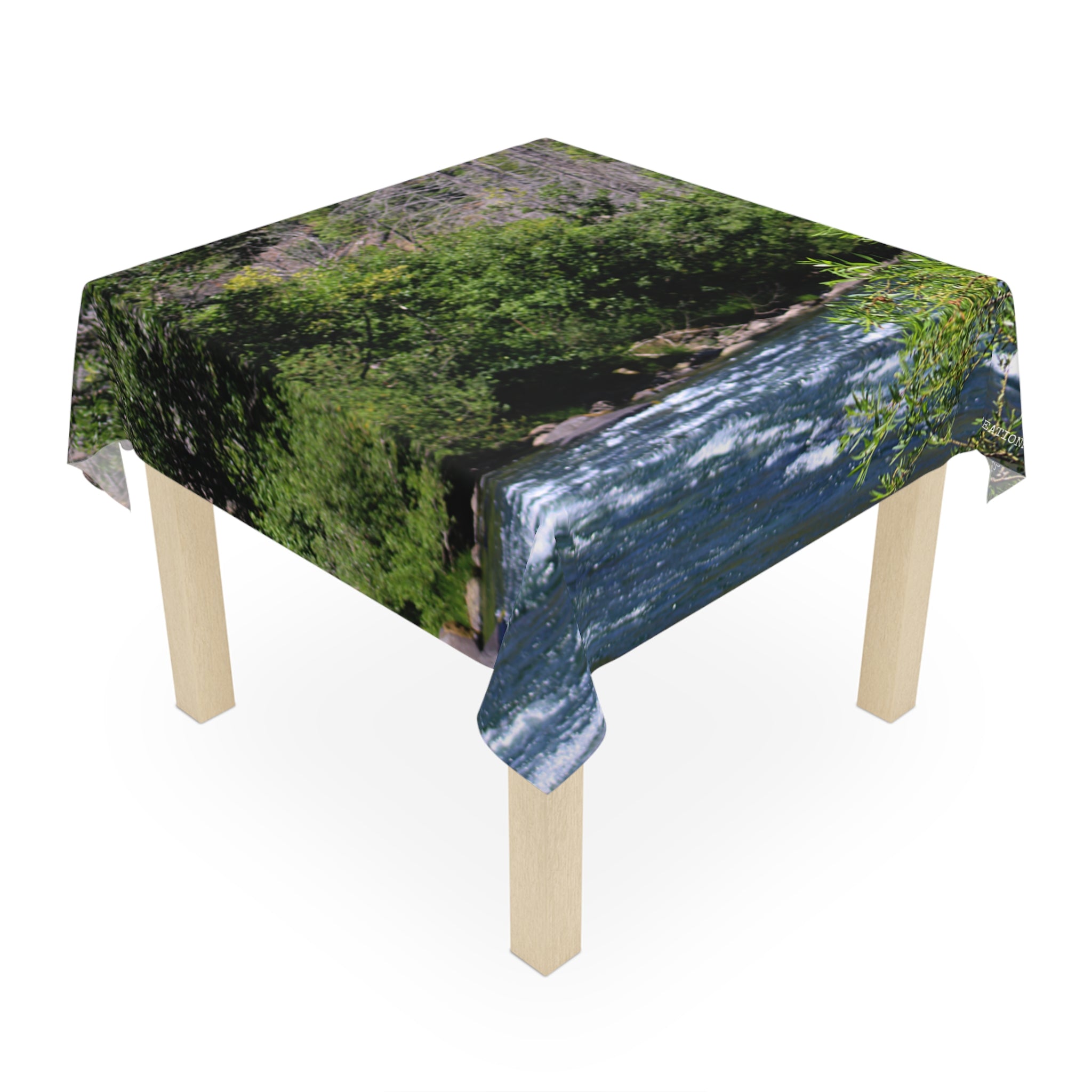Tablecloth with a scenic river and green foliage pattern.