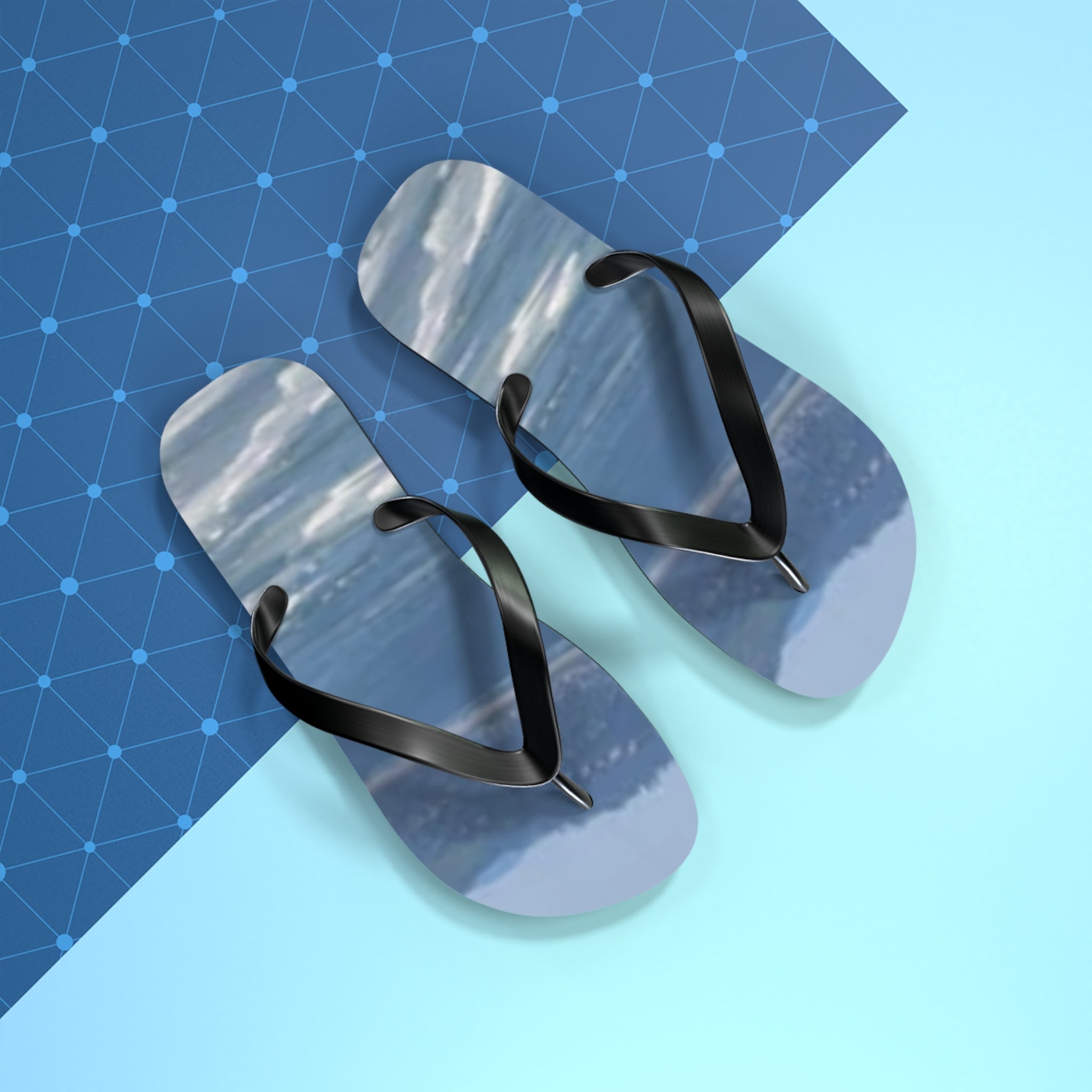 Pair of black flip-flops with mountain scene printed on soles.