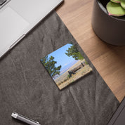 Sticky note with landscape picture of trees, sky, and distant building.