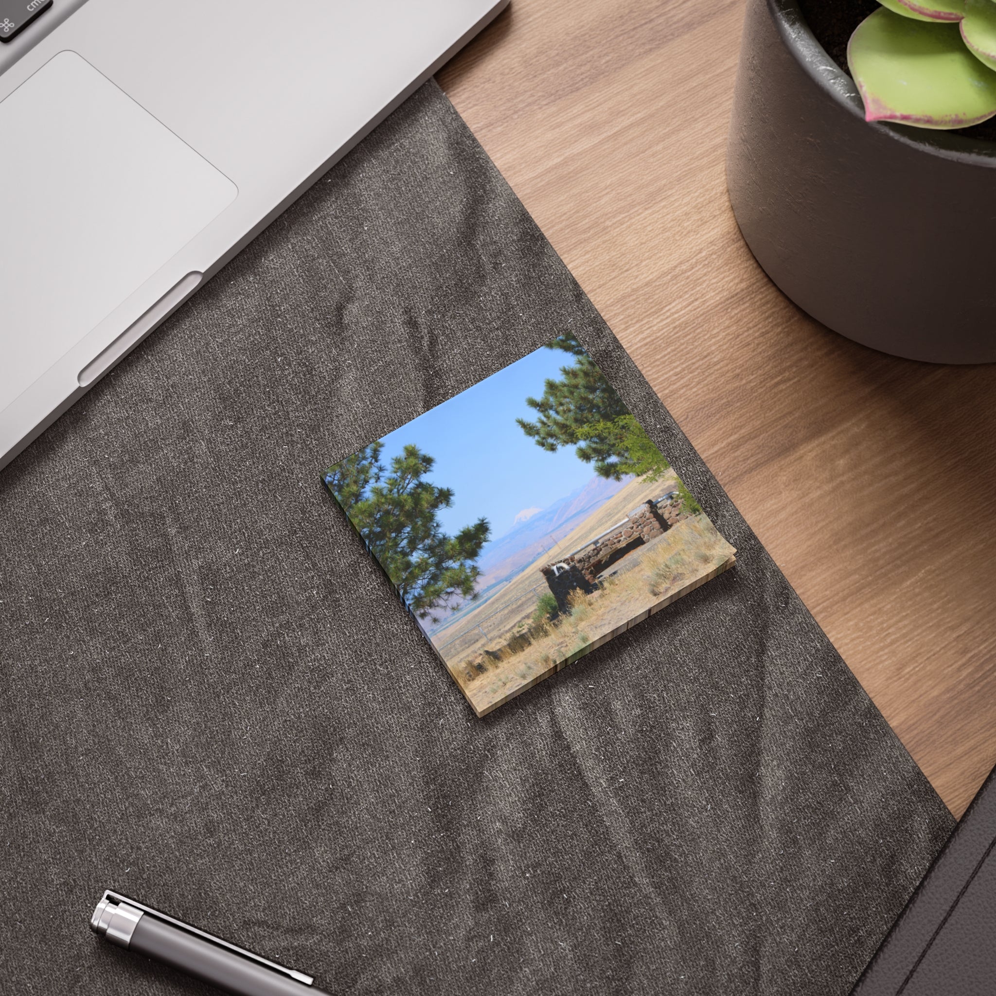 Sticky note with landscape picture of trees, sky, and distant building.