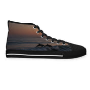 High-top sneakers with dolphins jumping in ocean waves at sunset.
