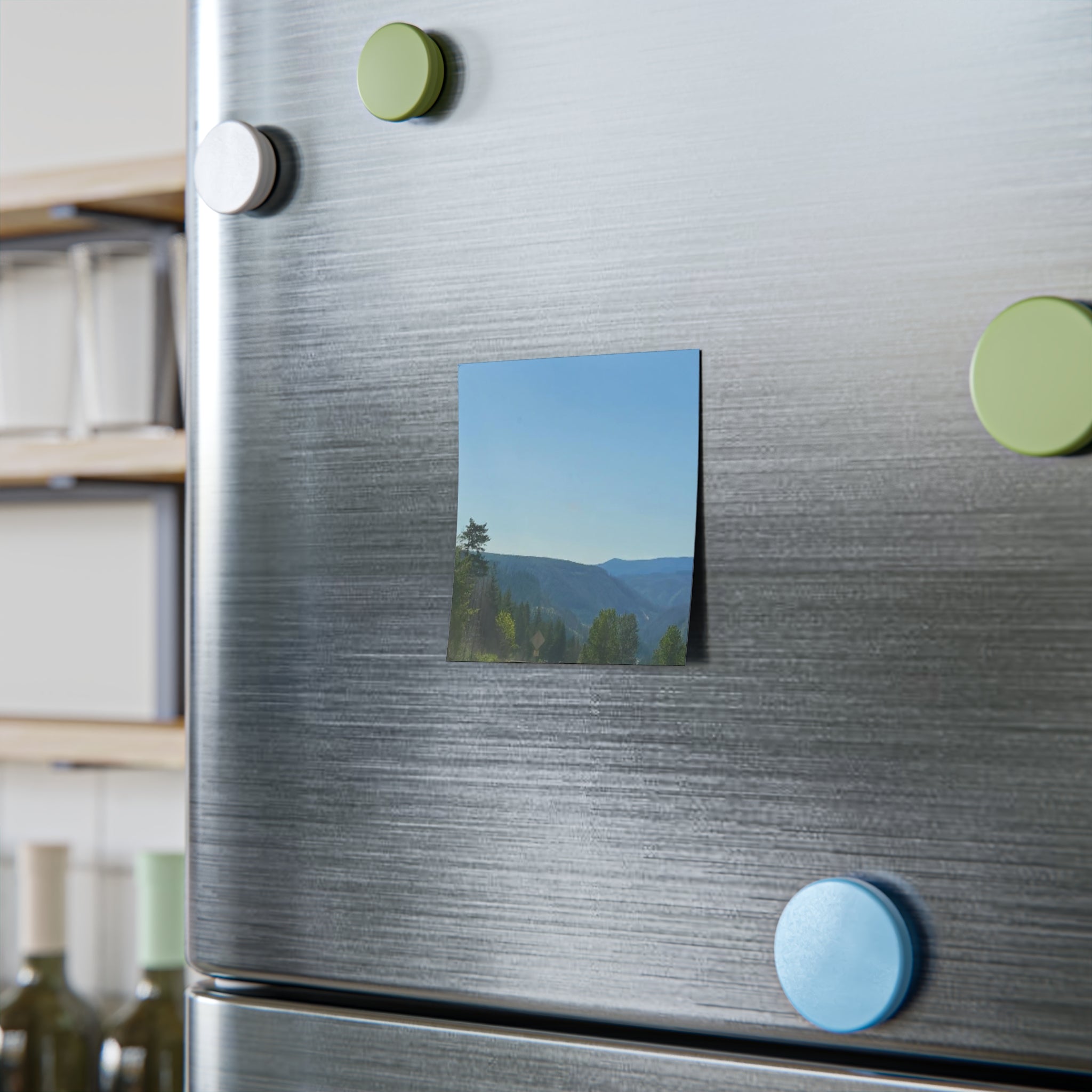 Square magnet featuring a landscape photo of a valley with trees under a blue sky.