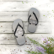 Flip-flops with a beach scene printed on soles, resting on weathered wood.