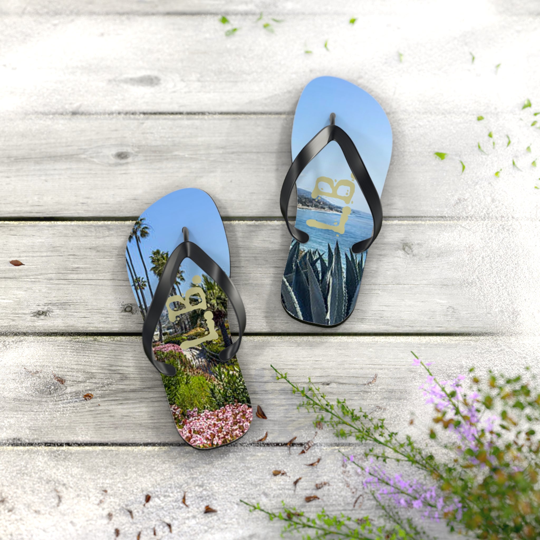 Flip-flops with a beach and floral scene, on a wooden surface.