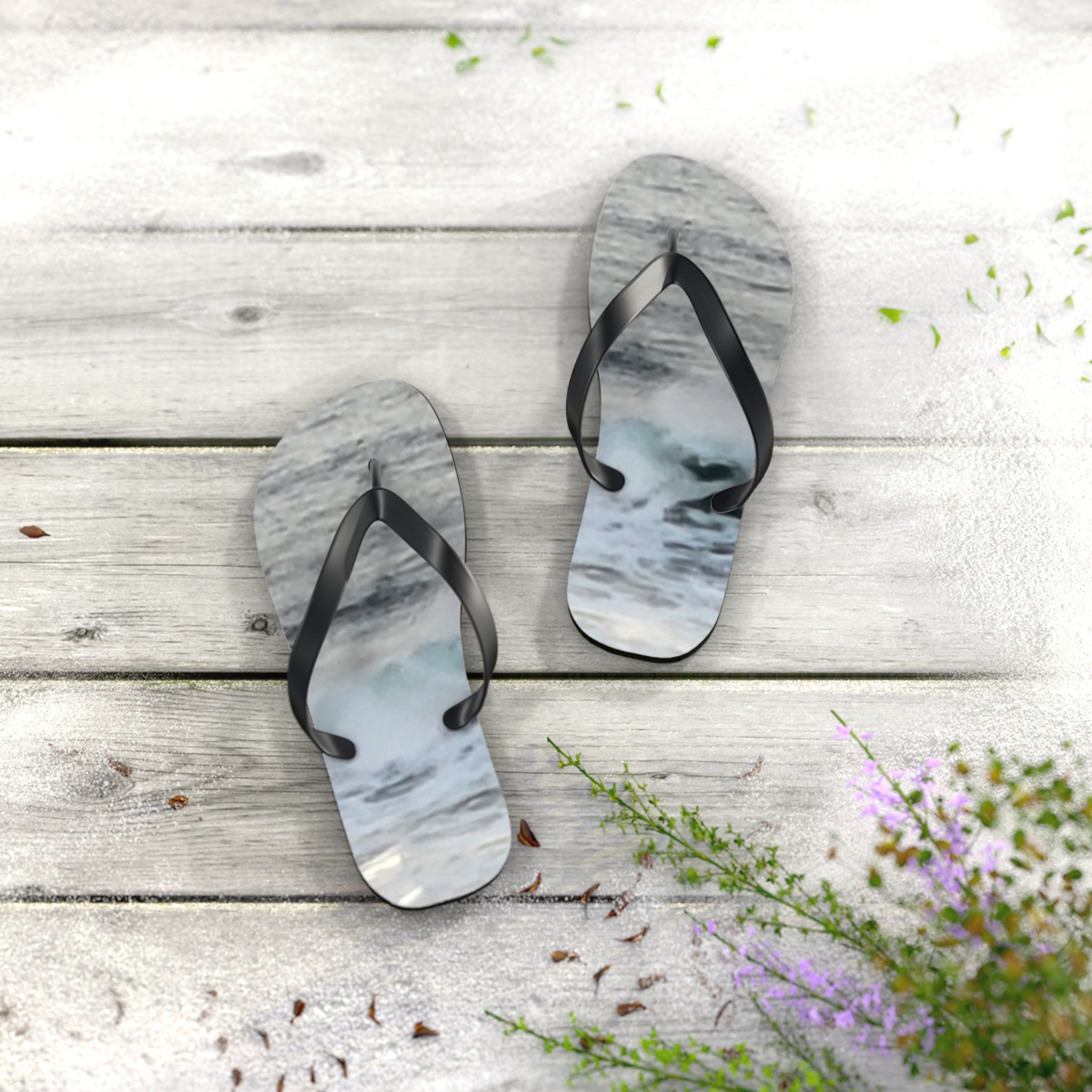 Flip-flops with a wave design on a wooden boardwalk with flowers.