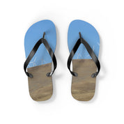Flip-flops with wind turbines on a grassy hill and blue sky.