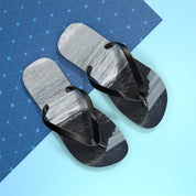 Black flip-flops with a scenic mountain image on a blue geometric background.