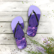 Purple flip-flops with a landscape print on a wooden surface.