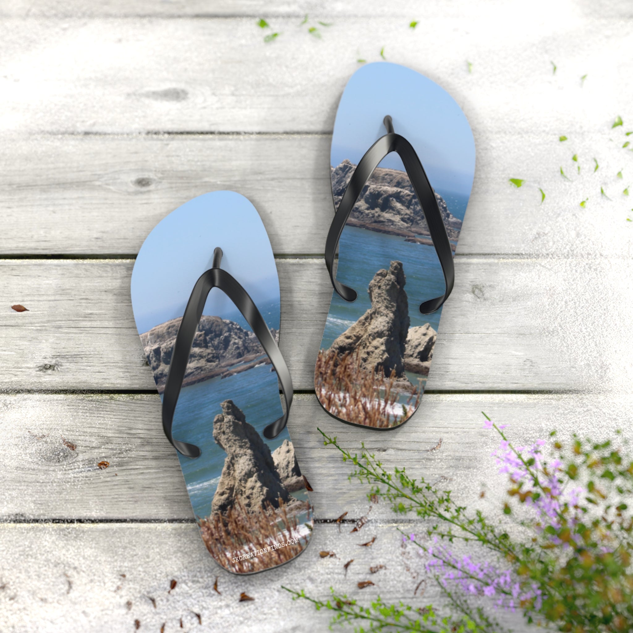Flip-flops featuring a rocky ocean coastline scene, laid flat on wooden planks.