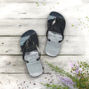 Flip-flops with a wave and rock graphic on a light wooden surface.