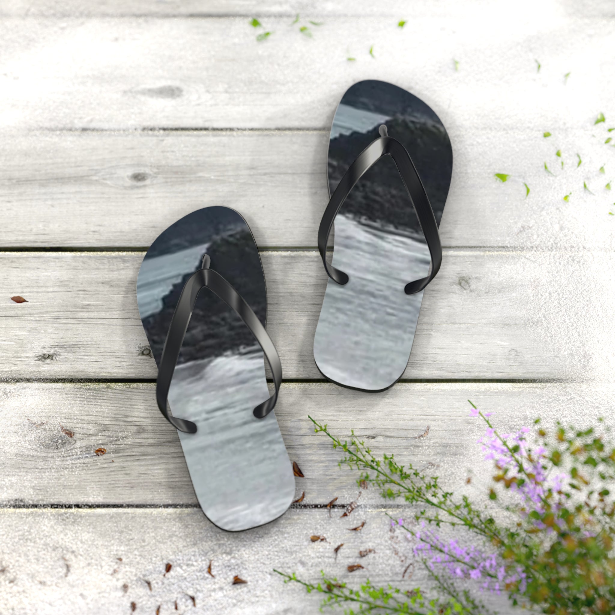 Flip-flops with a wave and rock graphic on a light wooden surface.
