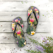 Flip-flops with pink tulips and purple flowers on a wooden surface.