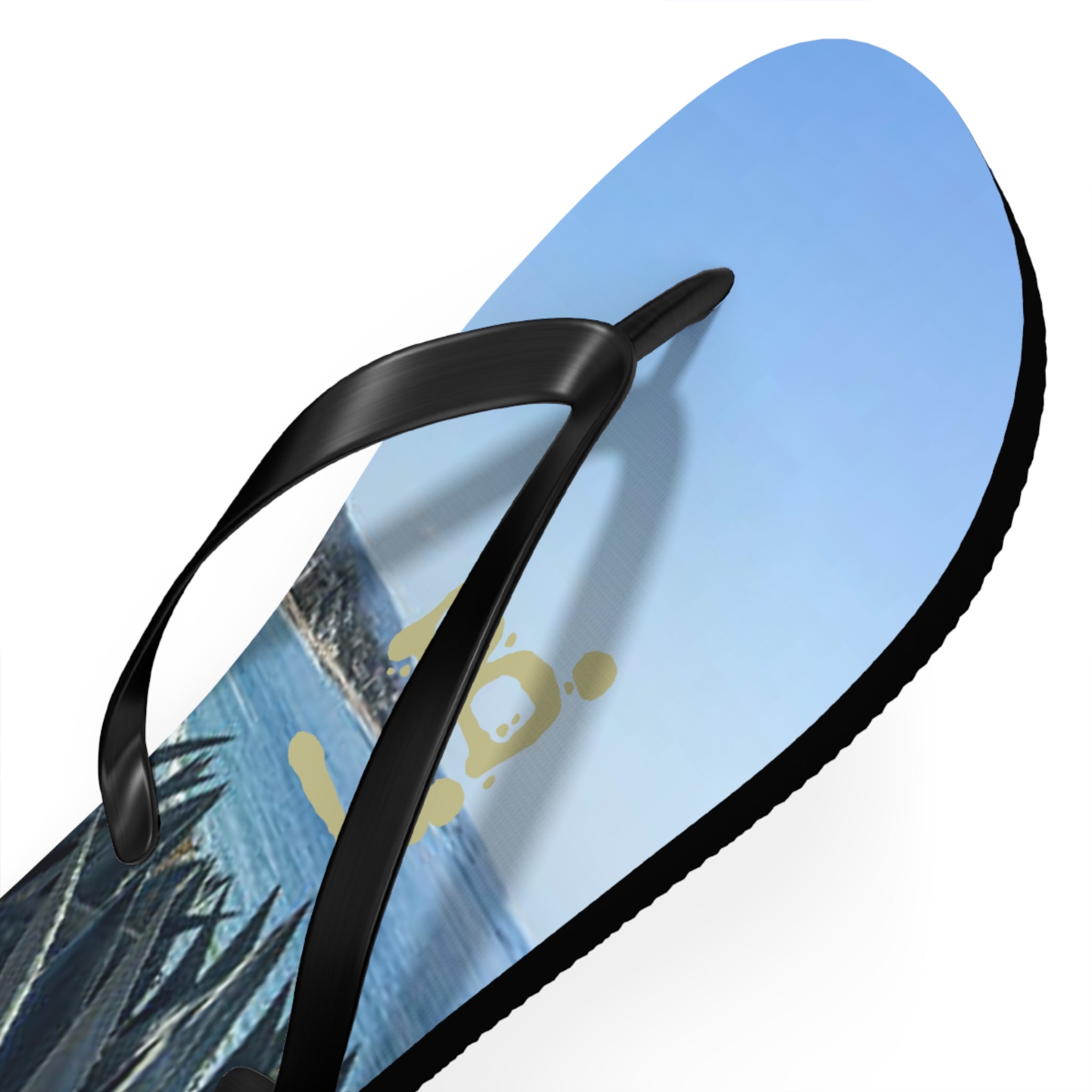 Black flip-flop with a golden logo and tropical beach scene on the sole.