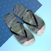 Black flip-flops with ocean wave print on a blue and white background.