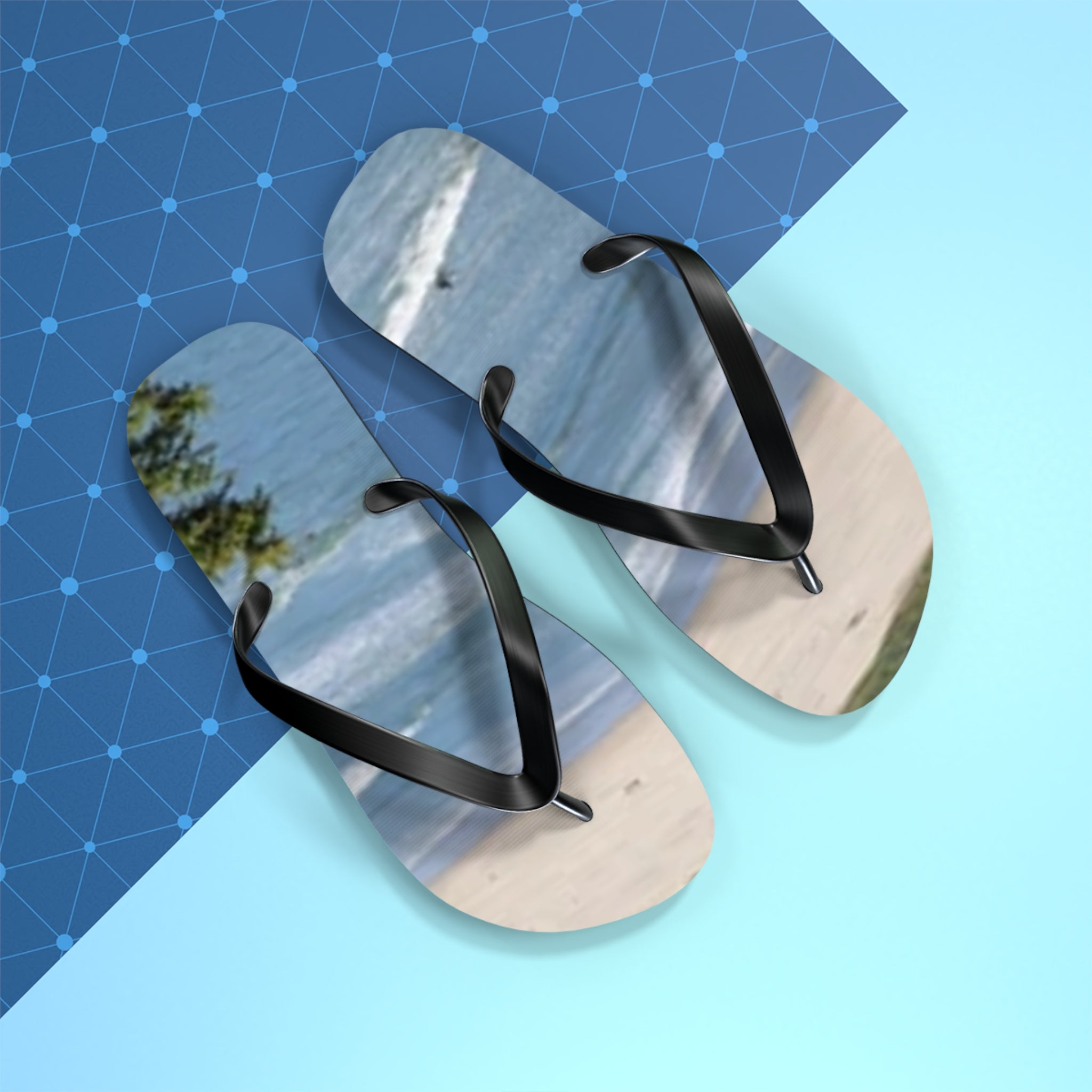 Flip-flops with a beach scene and water print on a blue patterned background.