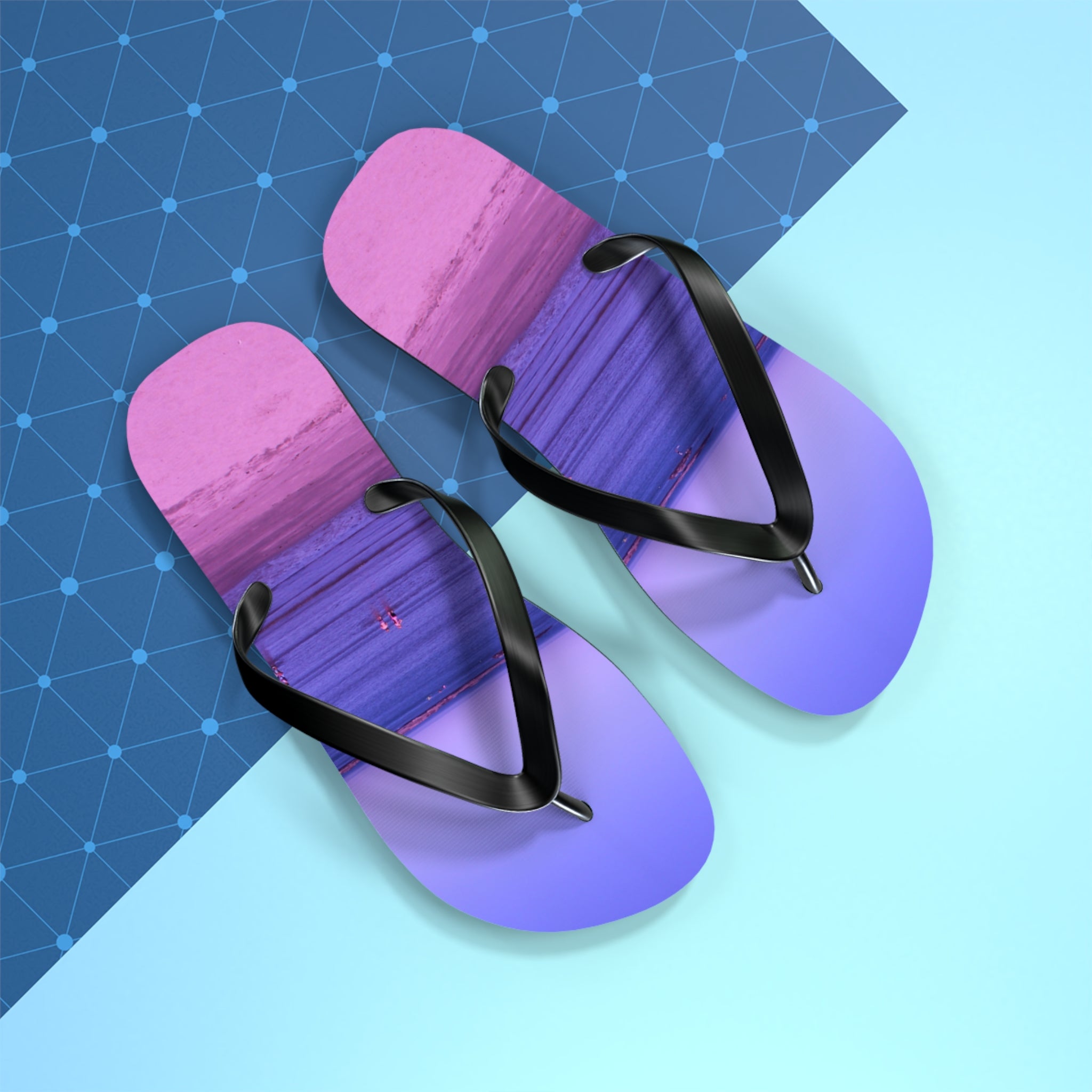 Purple and pink ombre flip-flops with black straps on a blue and geometric background.