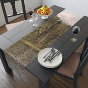 Table runner with a lake and forest scene, set on a dark table.