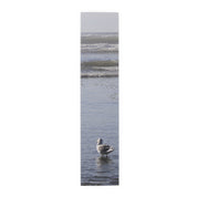 Seagull standing in shallow ocean water with waves in background.