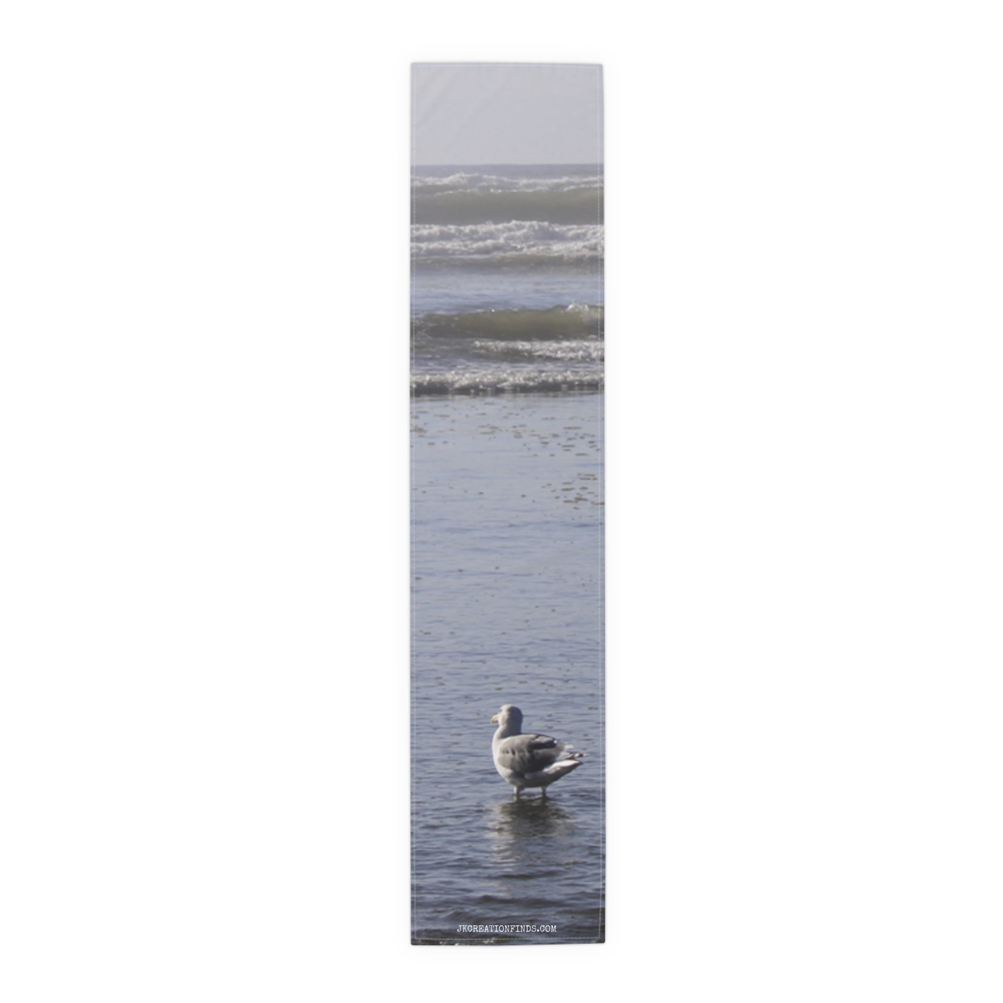 Seagull standing in shallow ocean water with waves in background.